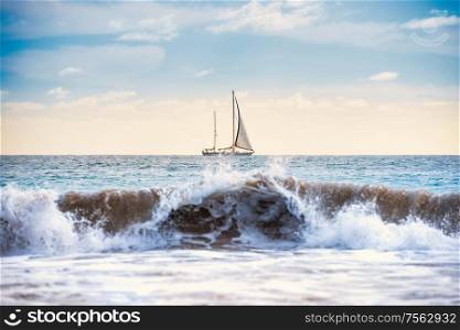 Seascape with white sailboat, blue water and surf wave on foreground
