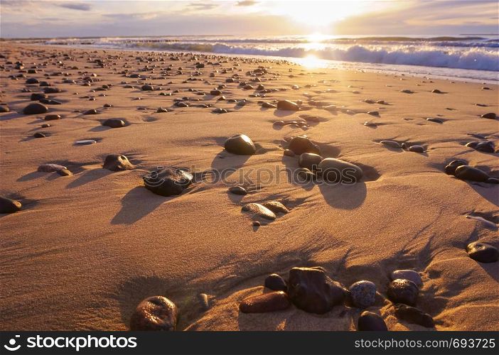 seashore at sunset, sea stones in the light of the sun. sea stones in the light of the sun, seashore at sunset