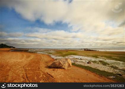 seashore with big stone under clouds