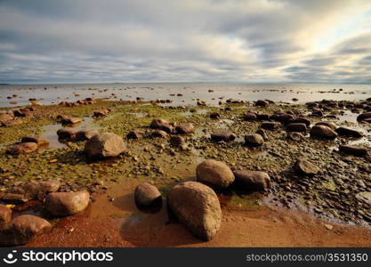 seashore with big stones under dark cloudy sky