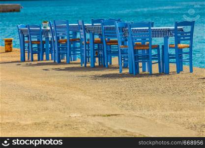Seaside blue table and chairs open cafe outdoor restaurant in Greece on sea shore. Summer vacation on resort.. Open cafe outdoor restaurant in Greece on sea shore