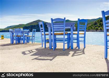 Seaside blue table and chairs open cafe outdoor restaurant in Greece on sea shore. Summer vacation on resort.. Open cafe outdoor restaurant in Greece on sea shore