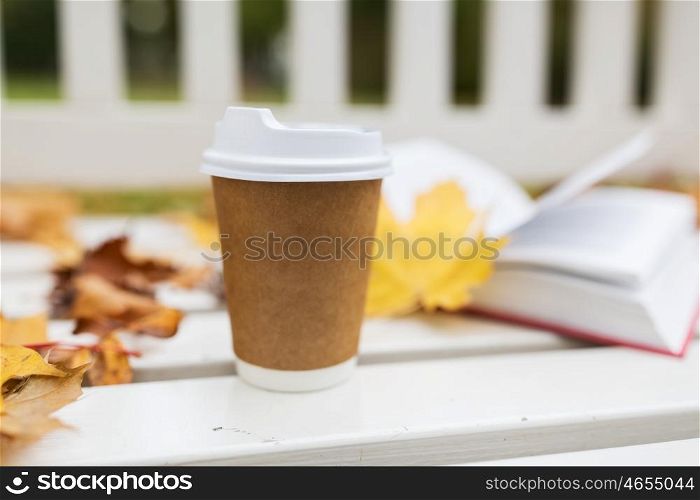 season, advertisement and drinks concept - coffee in paper cup on bench in autumn park