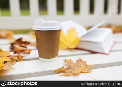 season, advertisement and drinks concept - coffee in paper cup on bench in autumn park