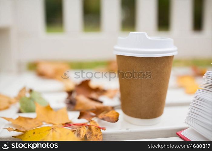 season, advertisement and drinks concept - coffee in paper cup on bench in autumn park