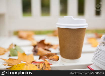 season, advertisement and drinks concept - coffee in paper cup on bench in autumn park