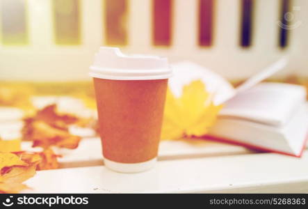 season, advertisement and drinks concept - coffee in paper cup on bench in autumn park. coffee drink in paper cup on bench at autumn park