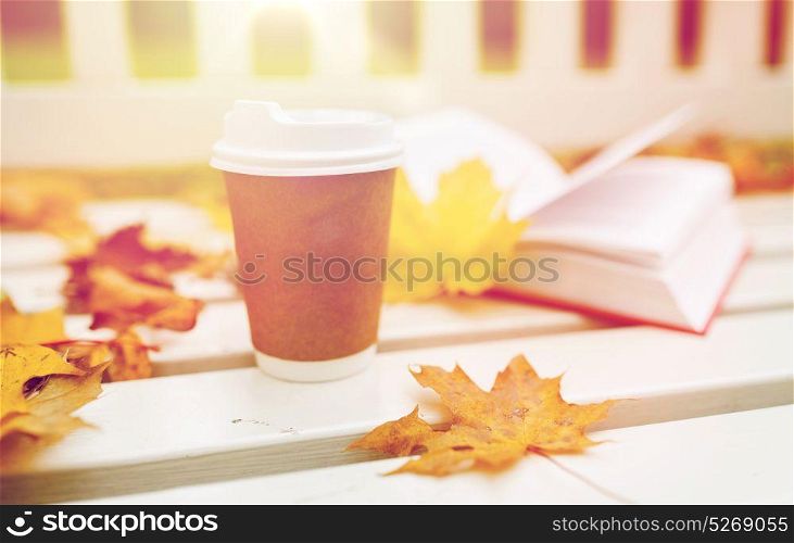 season, advertisement and drinks concept - coffee in paper cup on bench in autumn park. coffee drink in paper cup on bench at autumn park