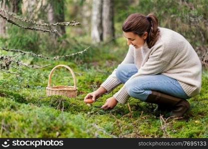 season and leisure people concept - young woman with basket and knife cutting mushroom in autumn forest. young woman picking mushrooms in autumn forest