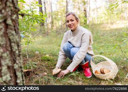season and leisure people concept - young woman with basket picking mushrooms in autumn forest. young woman picking mushrooms in autumn forest