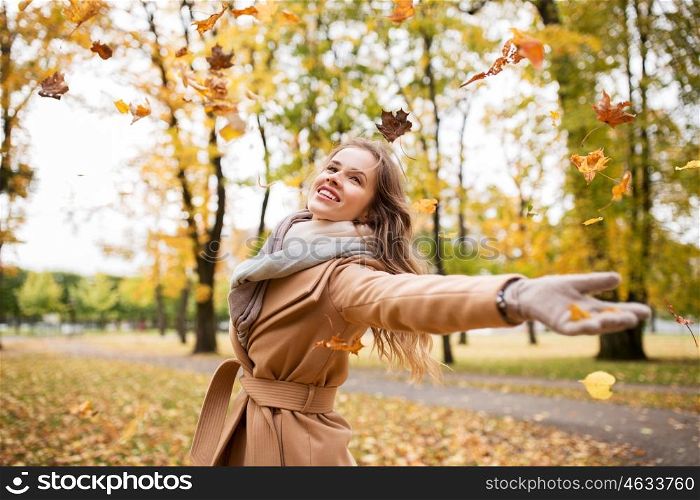 season and people concept - beautiful happy young woman having fun with leaves in autumn park. happy woman having fun with leaves in autumn park