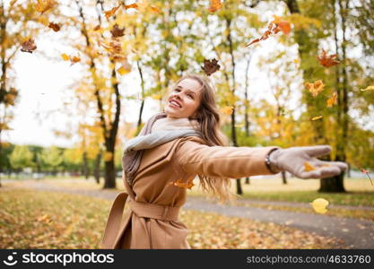 season and people concept - beautiful happy young woman having fun with leaves in autumn park. happy woman having fun with leaves in autumn park