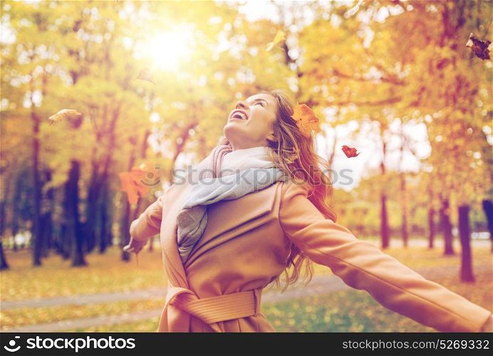 season and people concept - beautiful happy young woman having fun with leaves in autumn park. happy woman having fun with leaves in autumn park