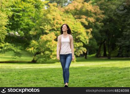 season and people concept - beautiful happy young woman walking in summer park. beautiful happy young woman walking in summer park