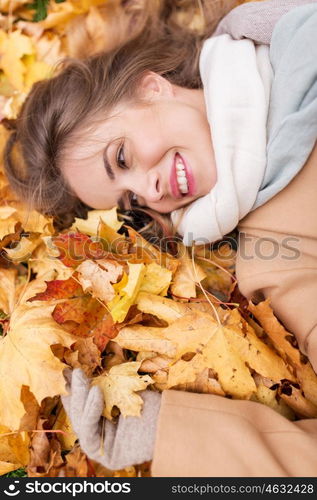 season and people concept - beautiful young woman lying on ground and autumn leaves. beautiful happy woman lying on autumn leaves