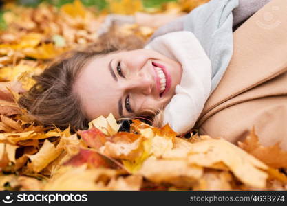 season and people concept - beautiful young woman lying on ground and autumn leaves. beautiful happy woman lying on autumn leaves