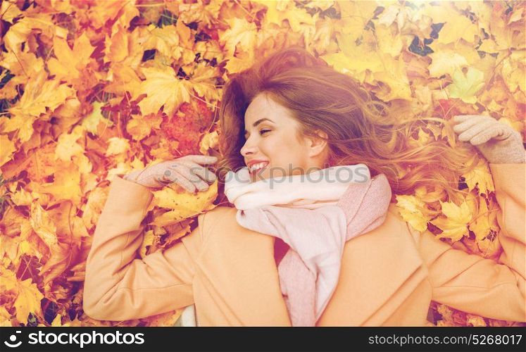 season and people concept - beautiful young woman lying on ground and autumn leaves. beautiful happy woman lying on autumn leaves