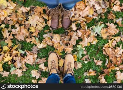 season and people concept - couple of feet in boots with autumn leaves on ground. couple of feet in boots and autumn leaves