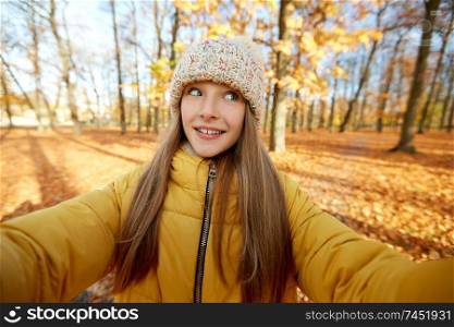 season and people concept - happy girl taking selfie at autumn park. happy girl taking selfie at autumn park