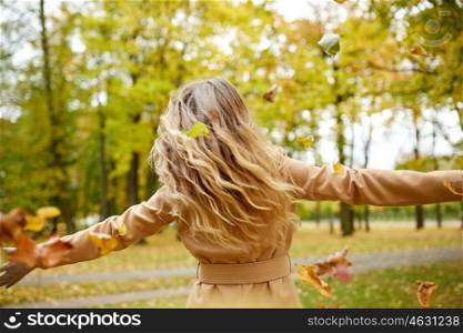 season and people concept - happy young woman having fun with leaves in autumn park. happy woman having fun with leaves in autumn park