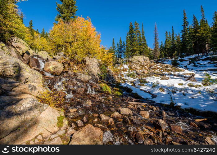 Season changing, first snow and autumn aspen trees in Rocky Mountain National Park, Colorado, USA.