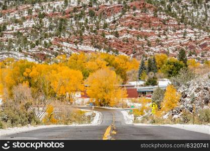 Season changing, first snow and autumn trees along wet highway in Colorado, USA.