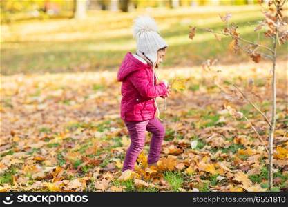 season, childhood and people concept - happy little girl with maple leaf at autumn park. happy little girl with maple leaf at autumn park. happy little girl with maple leaf at autumn park