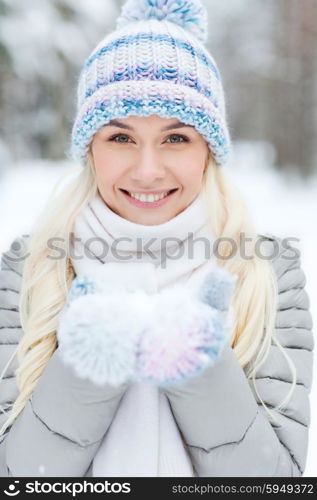 season, christmas and people concept - happy smiling young woman holding snow on palms in winter forest