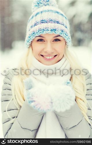 season, christmas and people concept - happy smiling young woman holding snow on palms in winter forest