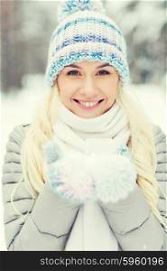 season, christmas and people concept - happy smiling young woman holding snow on palms in winter forest