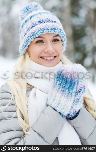 season, christmas and people concept - happy smiling young woman in winter forest