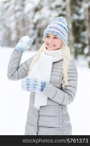 season, christmas and people concept - happy smiling young woman throwing snowball in winter forest