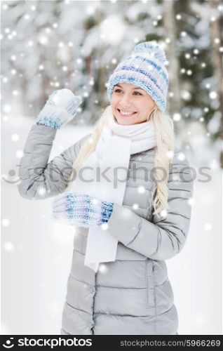 season, christmas and people concept - happy smiling young woman throwing snowball in winter forest