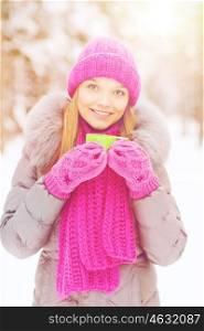 season, christmas, drinks and people concept - happy smiling young woman with cup drinking hot tea in winter forest