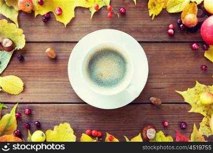 season, drink and morning concept - close up of coffee cup on wooden table with autumn leaves