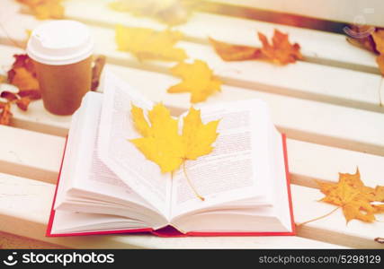 season, education and literature concept - open book and coffee cup on bench in autumn park. open book and coffee cup on bench in autumn park