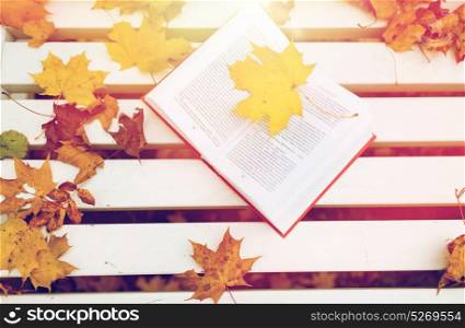 season, education and literature concept - open book on bench in autumn park. open book on bench in autumn park