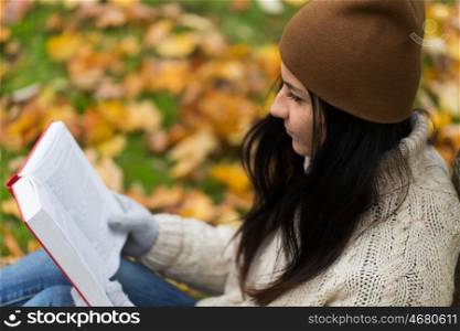 season, education, literature and people concept - close up of woman reading book in autumn park
