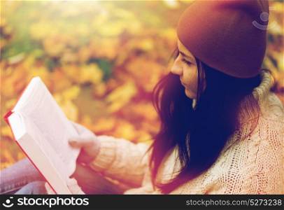 season, education, literature and people concept - close up of woman reading book in autumn park. close up of woman reading book in autumn park