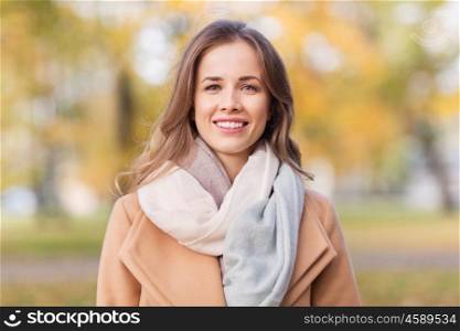 season, emotions, facial expression and people concept - beautiful happy young woman smiling in autumn park