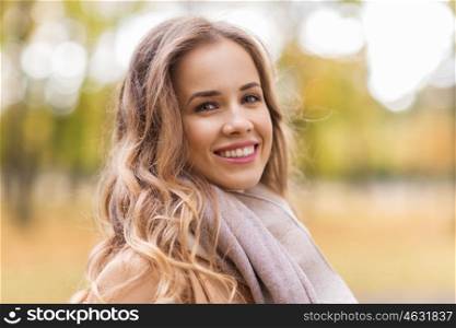season, emotions, facial expression and people concept - beautiful happy young woman smiling in autumn park