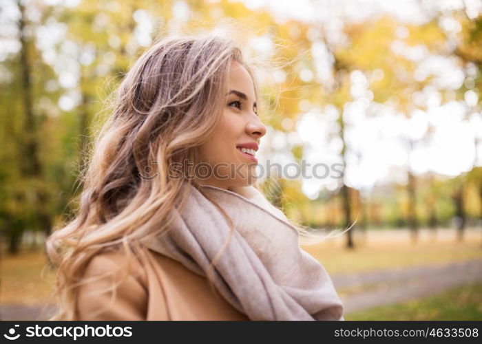 season, emotions, facial expression and people concept - beautiful happy young woman smiling in autumn park