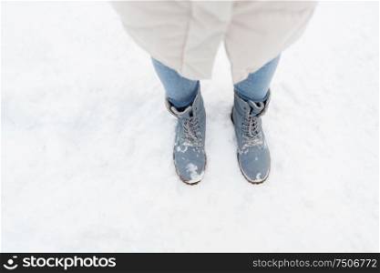season, footwear and people concept - female feet in winter shoes on snow from top. female feet in winter shoes on snow from top