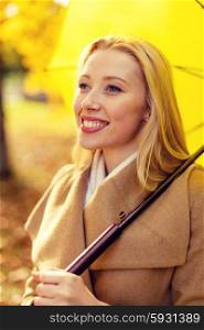 season, happiness and people concept - smiling woman with umbrella in autumn park