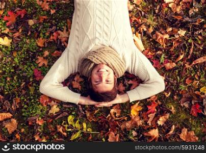 season, happiness and people concept - smiling young man lying on ground or grass and fallen leaves in autumn park