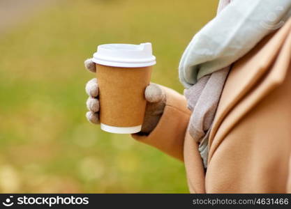 season, hot drinks, advertisement and people concept - close up of woman with coffee or tea disposable paper cup in autumn park