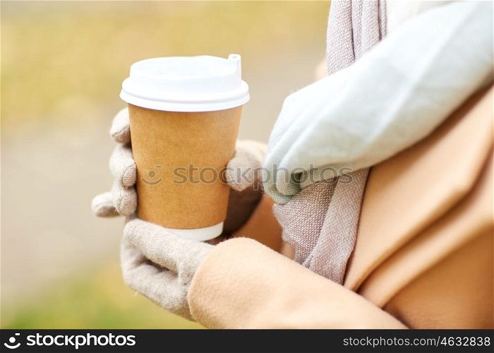 season, hot drinks, advertisement and people concept - close up of woman with coffee or tea disposable paper cup in autumn park