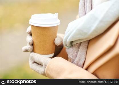 season, hot drinks, advertisement and people concept - close up of woman with coffee or tea disposable paper cup in autumn park