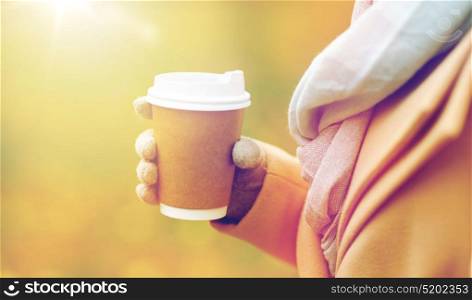season, hot drinks, advertisement and people concept - close up of woman with coffee or tea disposable paper cup in autumn park. close up of woman with coffee in autumn park