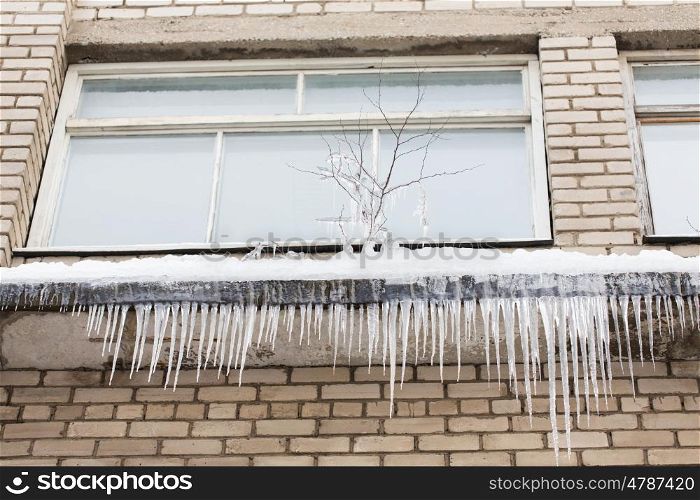 season, housing and winter concept - icicles on building or living house facade